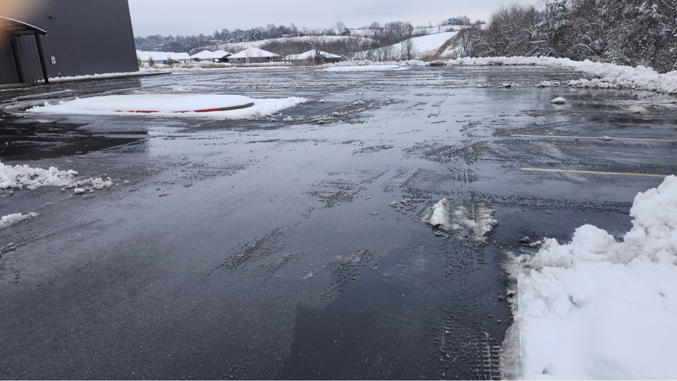 Cleared commercial parking lot with snow piles around the perimeter